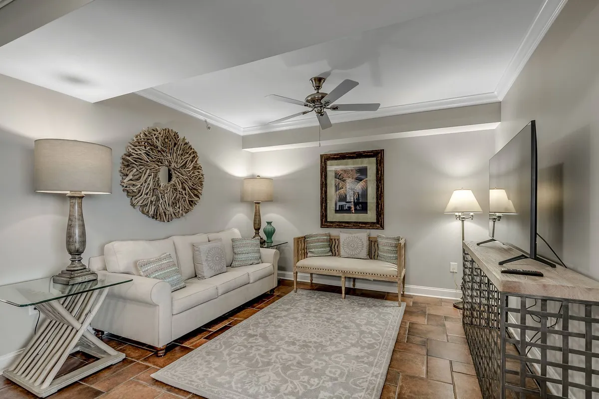 A comfortable living space with a cozy sofa, a decorative wall piece, table lamps for warm lighting, a central coffee table, and a TV as the entertainment focal point. The room is arranged for both socializing and unwinding, with a layout that easily supports movie marathons, games, or reading.