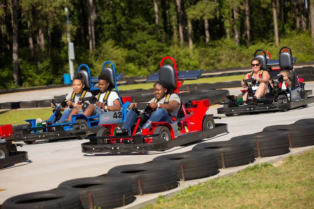 An energetic exterior view of a go-kart racetrack, where participants of all ages enjoy the thrill of racing. The brightly colored go-karts and lively atmosphere evoke a sense of adventure and family fun.